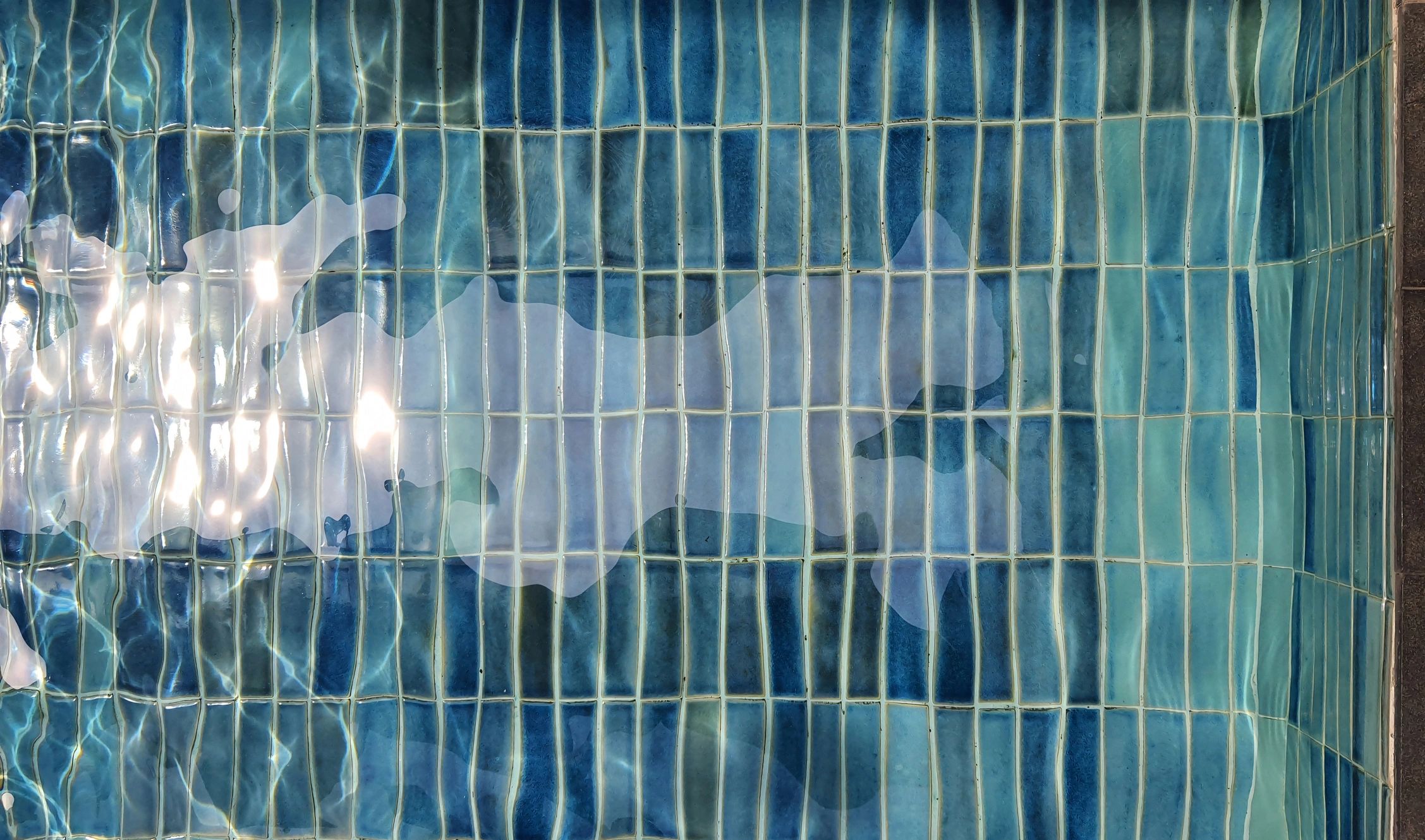 Blue mosaic pool tile under clear water